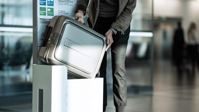 Homem checando tamanho da mala no aeroporto
